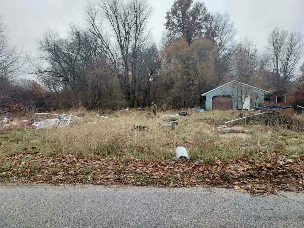 Overgrown property with debris and junk before trash and hoarder cleanout in Knox Indiana
